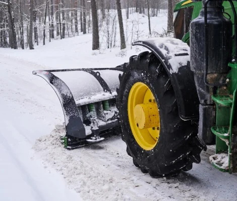 Tractor with a snow plow blade clearing a snowy road in Utah