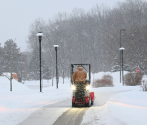 Snow blower clearing a lamp-lined walkway