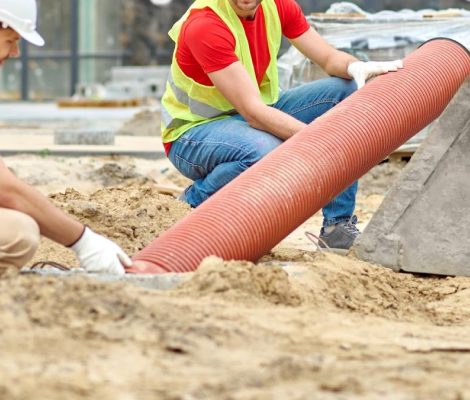 Technician fitting irrigation pipe in an open trench