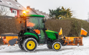 Tractor with a snow plow clearing a residential drive