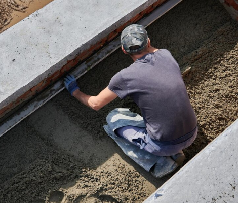 Worker installing a drainage line in a trench