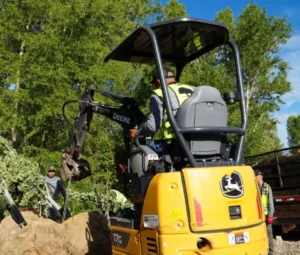 Compact excavator working among trees on a Park City property